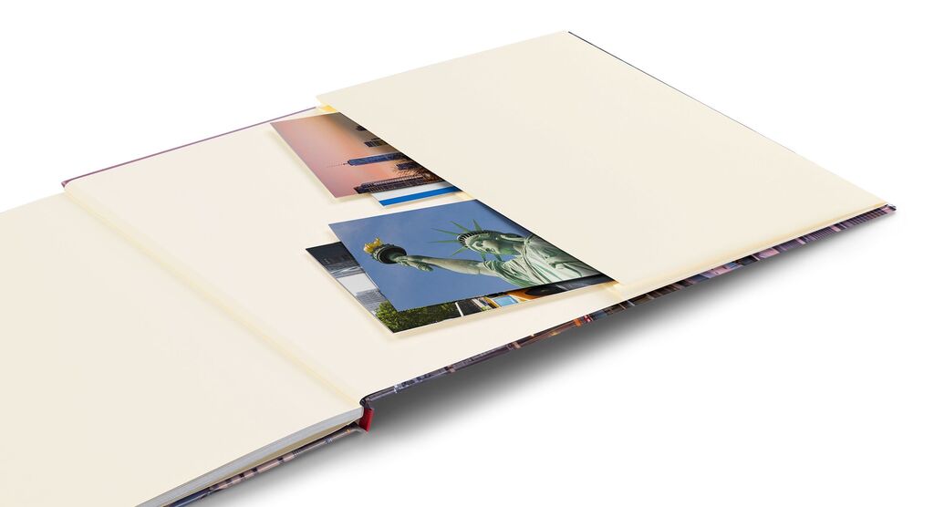 Ein offenes CEWE Fotobuch mit beige Seiten, das mehrere Fotos zeigt, darunter die Statue der Freiheit und eine Stadtansicht.