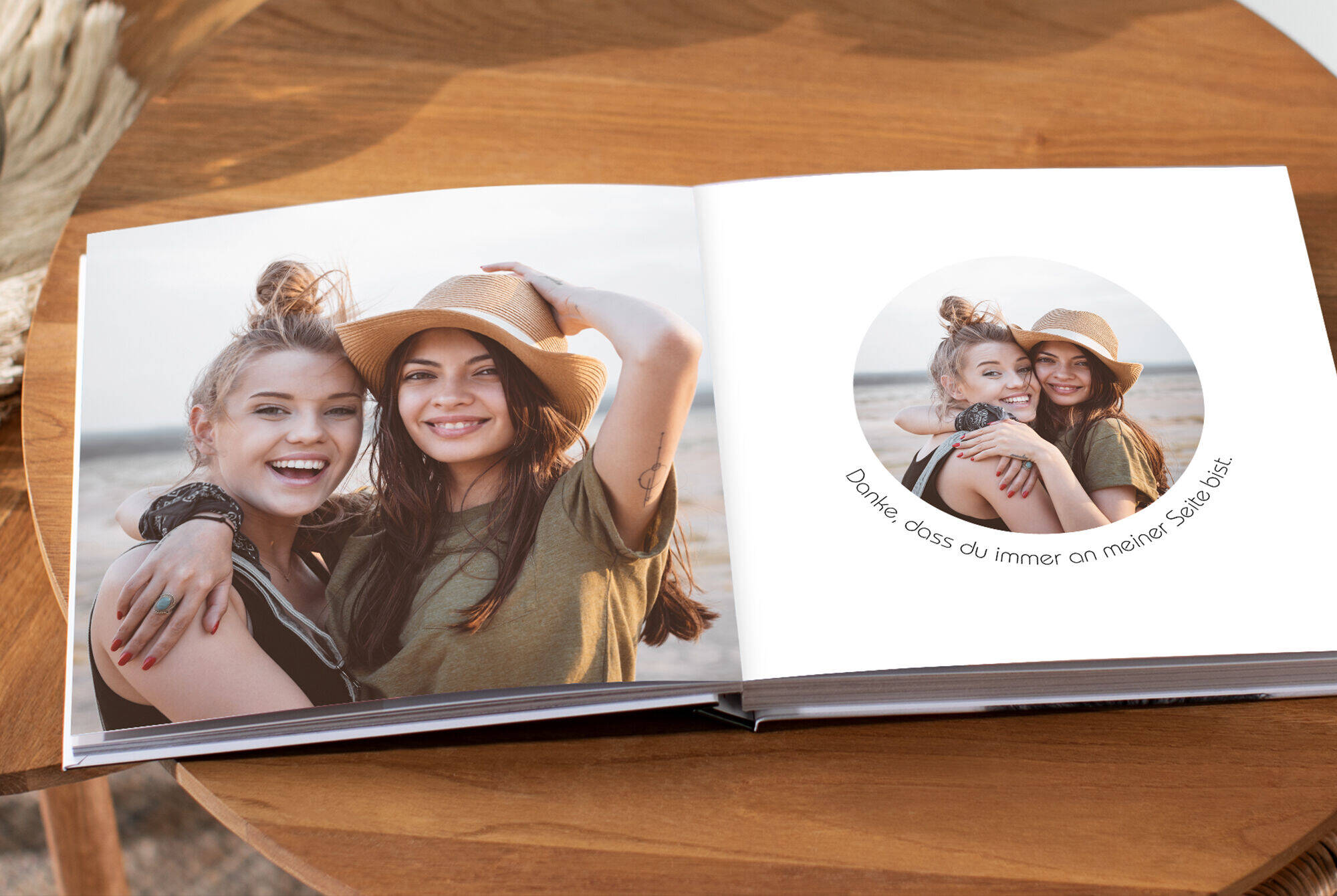 Zwei Frauen genießen den sonnigen Tag am Strand mit einem geöffneten Fotobuch zwischen ihnen.