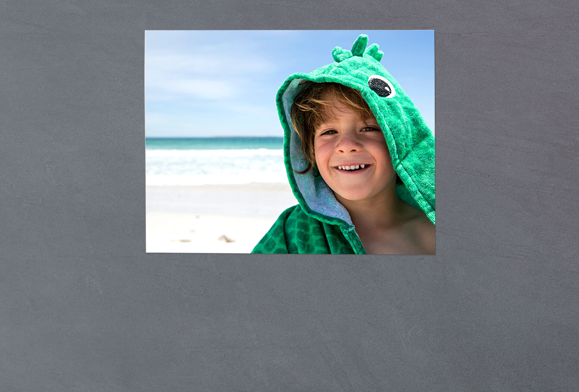 Ein Kind trägt einen grünen Kapuzenpulli am Strand und genießt die Sonne