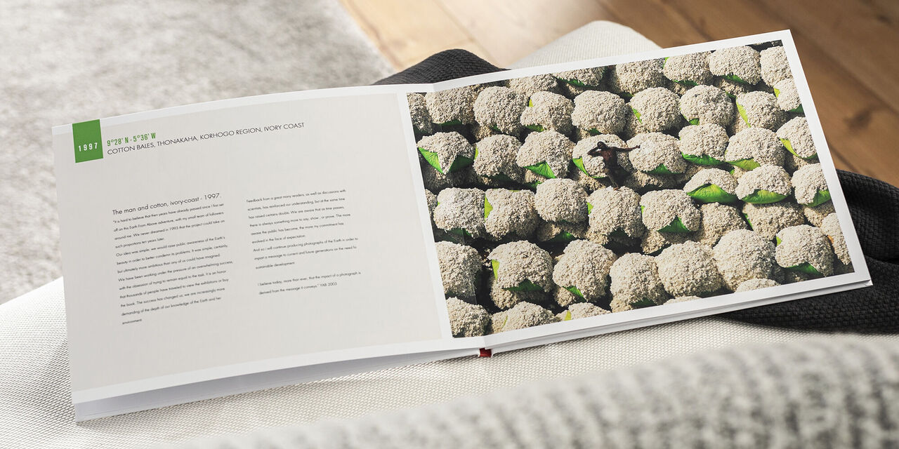 Das offene CEWE Fotobuch zeigt eine Doppelseite mit einer detailreichen Fotografie eines Beetes mit Brokkoli. Es sind viele grüne Köpfe zu sehen, umgeben von Erde. Die Seiten sind auf einem hellen Tisch platziert.