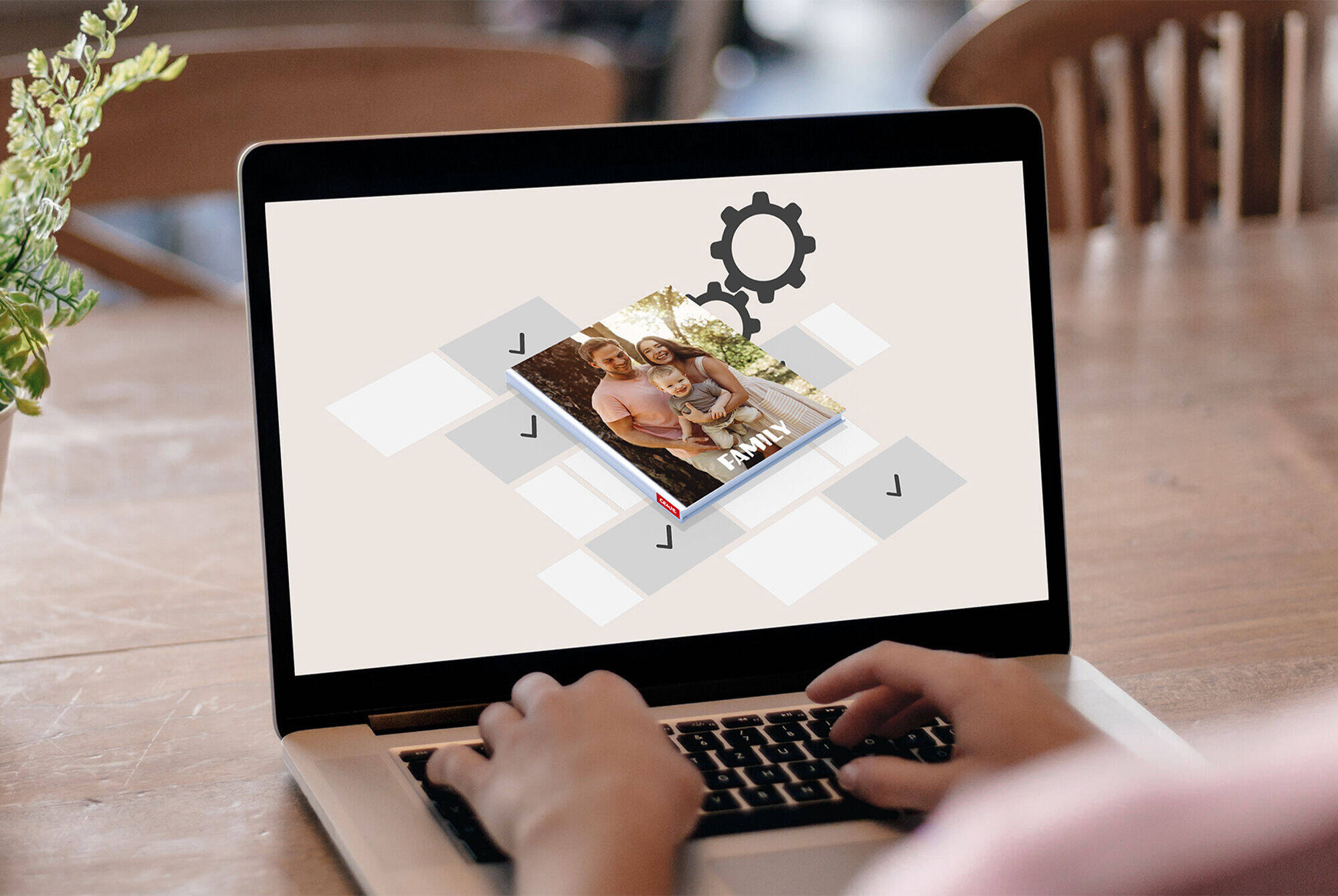 Person gestaltet ein CEWE Fotobuch auf ihrem Laptop mit kreativem Interface.