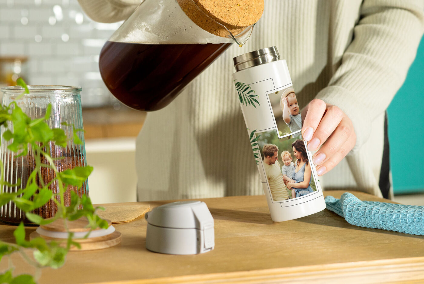 Person gießt Kaffee in eine individuelle Thermoskanne mit Fotos auf der Oberfläche
