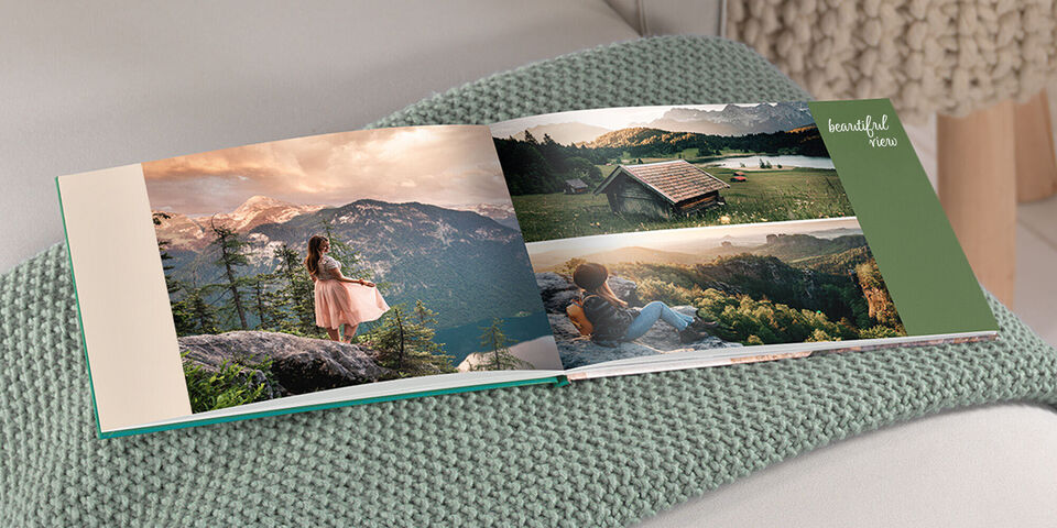 Offenes Fotobuch auf einer Couch mit Erinnerungen vom Urlaub in den Bergen