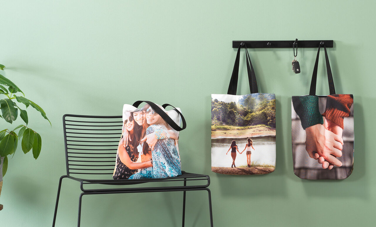 Drei dekorative Taschen mit persönlichen Fotos an einer Wand und einem Stuhl in einem modernen Raum.