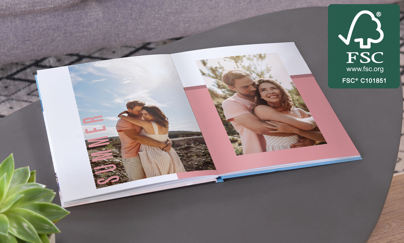 Ein offenes Fotobuch mit zwei Bildern von einem verliebten Paar, die sich umarmen und den Sommer genießen