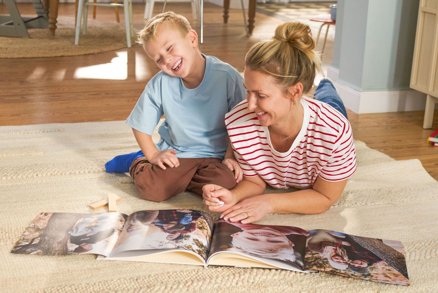 Eine Mutter und ihr Kind genießen gemeinsam ein CEWE FOTOBUCH auf dem Boden.