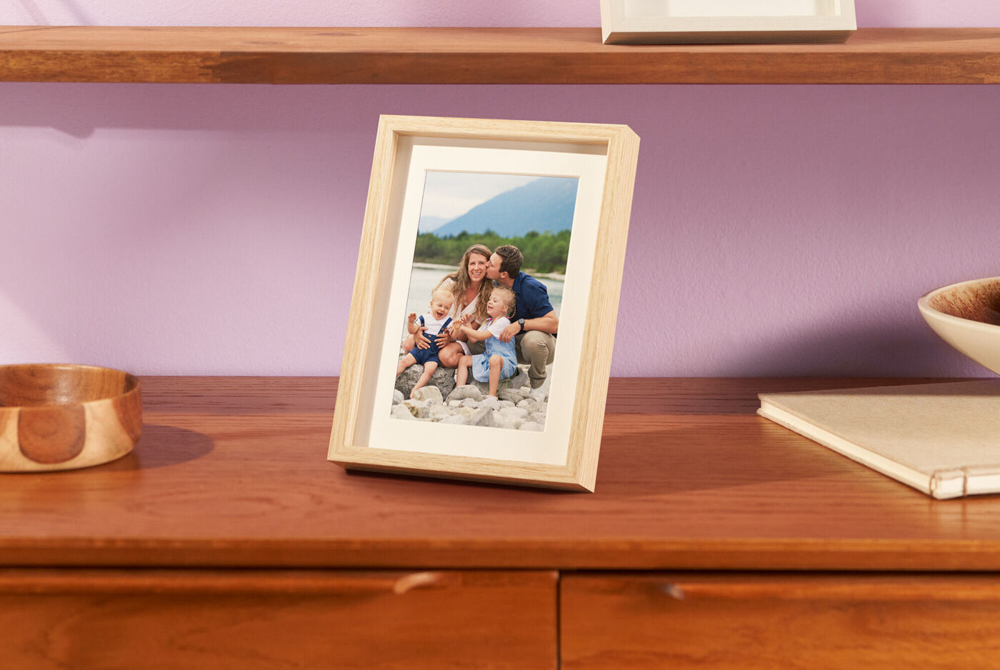 Ein fröhliches Familienfoto in einem Holzrahmen, auf einem Tisch platziert.