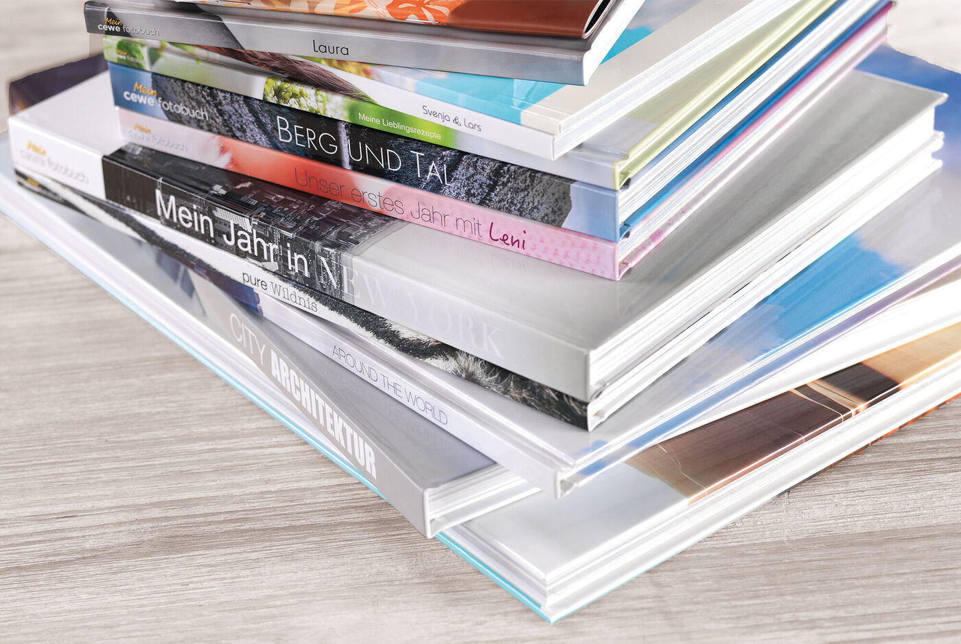 Eine kreative Anordnung verschiedener Fotobücher auf einem Tisch, die Geschichten und Erinnerungen enthalten. CEWE FOTOBUCH