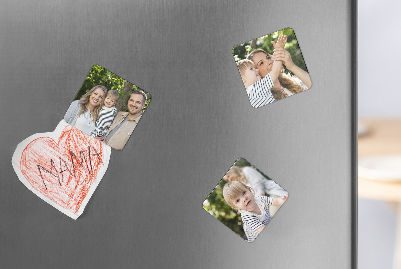 Magnetische Fotos und eine Zeichnung befestigt an einem Kühlschrank