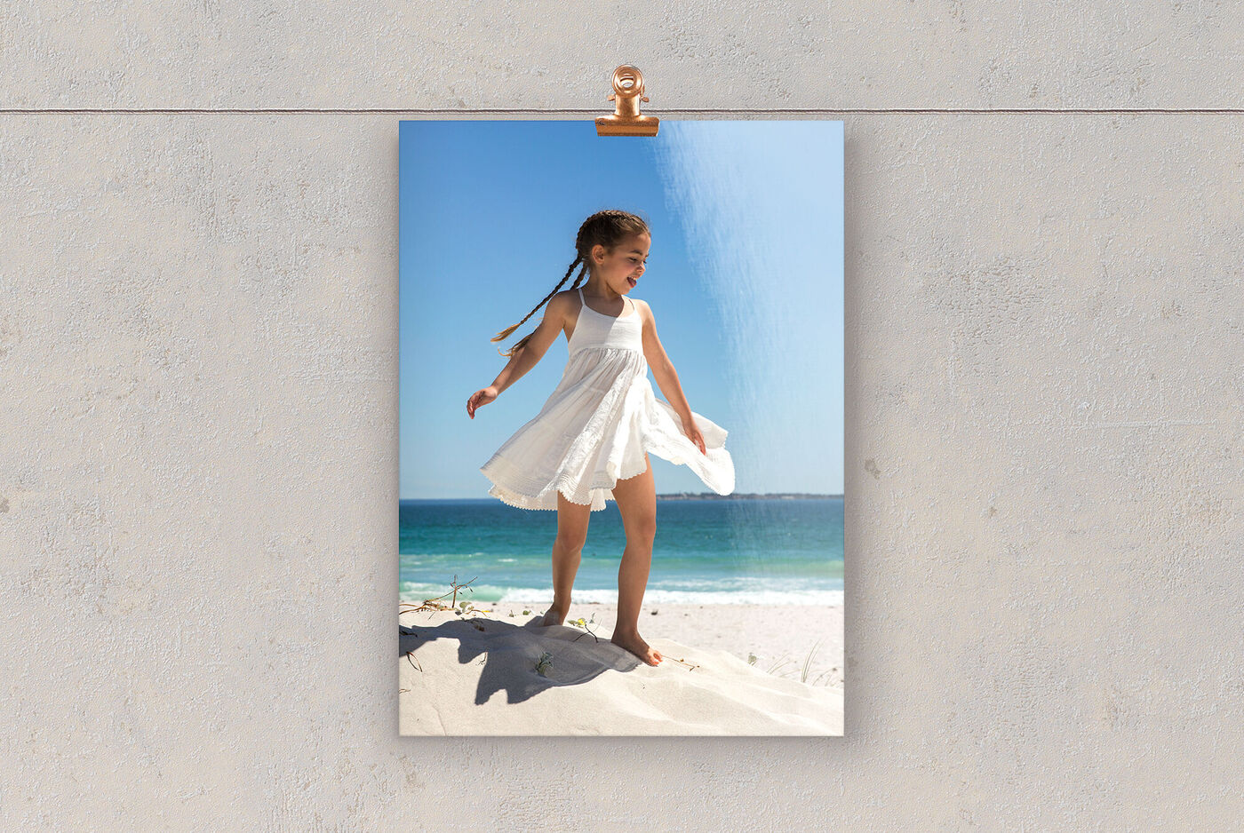 Ein Mädchen in einem weißen Kleid steht glücklich am Strand und genießt die Sonne.