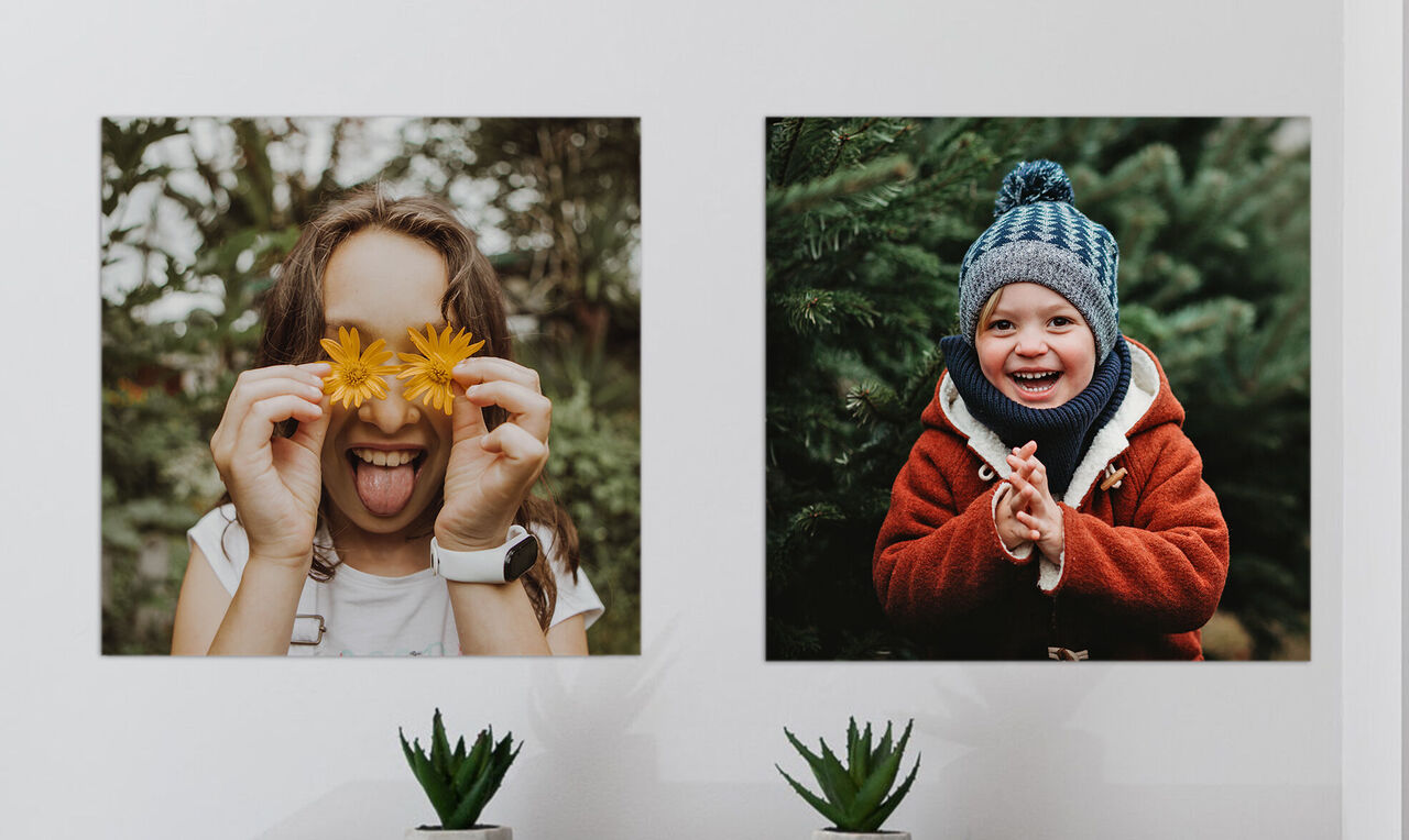 Zwei Kinder in der Natur, eines hält ein Blatt, das andere ist in einem roten Mantel, umgeben von grünen Pflanzen.