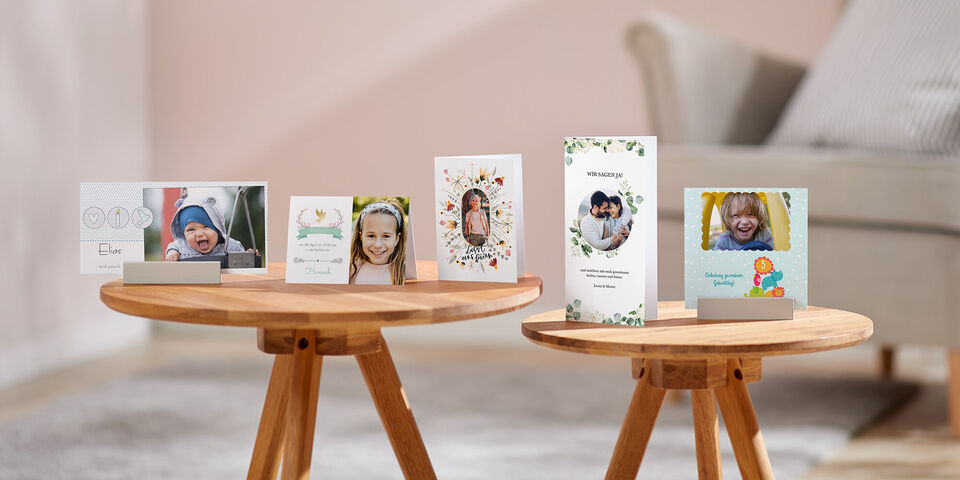 Verschiedene personalisierte Grußkarten und Fotos auf einem Holztisch