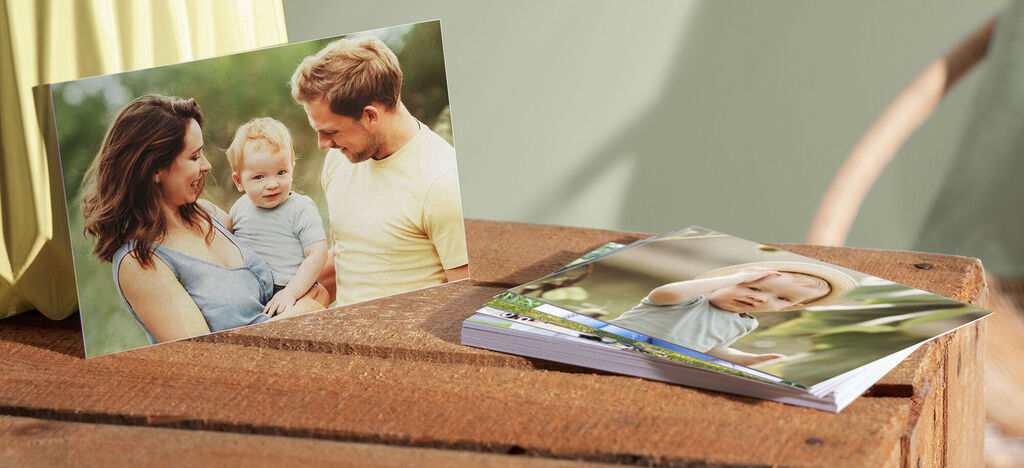 Familienfotokarten und ein Fotobuch auf einer Holzoberfläche, umgeben von Natur
