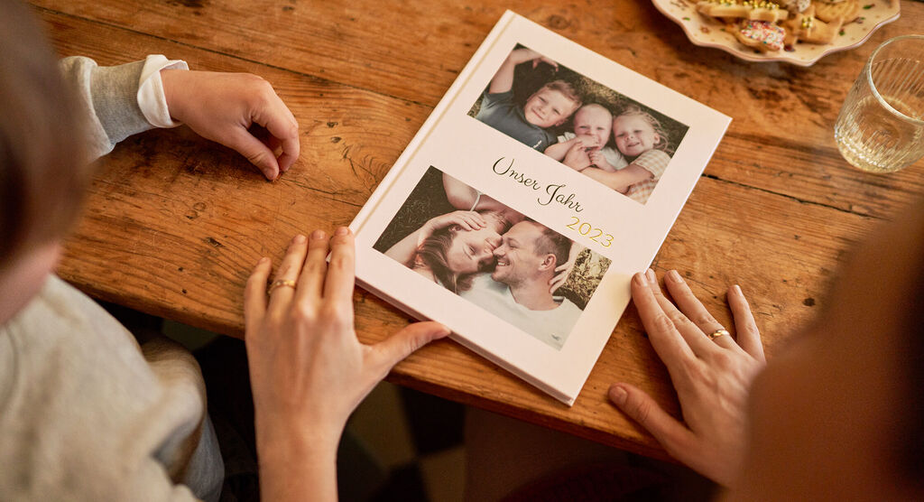 Eine Person betrachtet ein CEWE Fotobuch mit persönlichen Fotos.