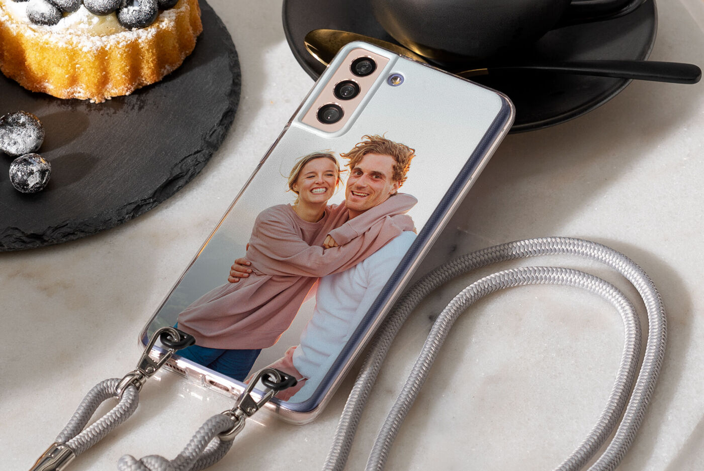 Ein personalisiertes Handyhülle mit einem Foto eines Paares, umgeben von einem Kaffee und einem leckeren Kuchen.