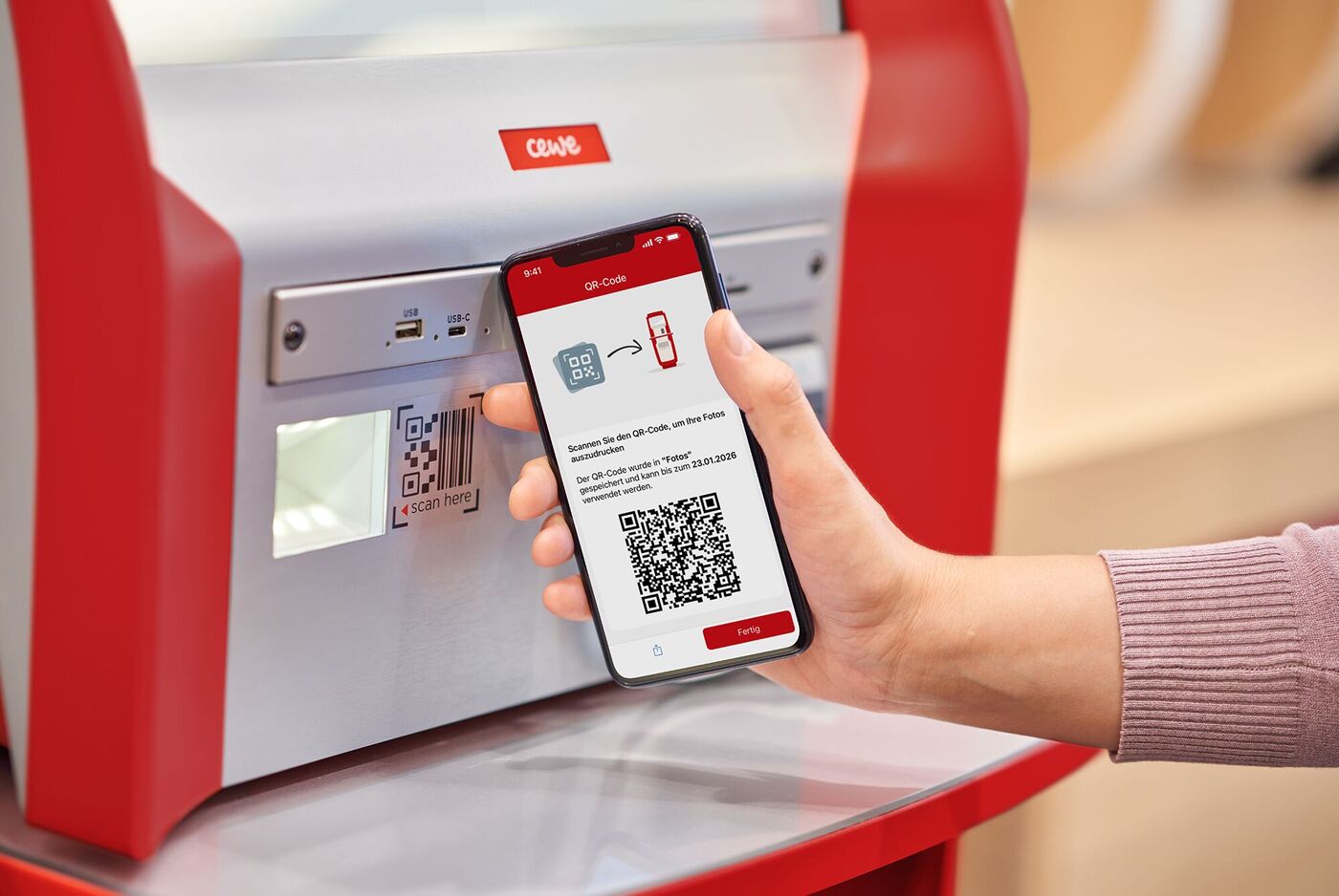 Eine Person scannt mit ihrem Smartphone einen QR-Code an einer Fotostation