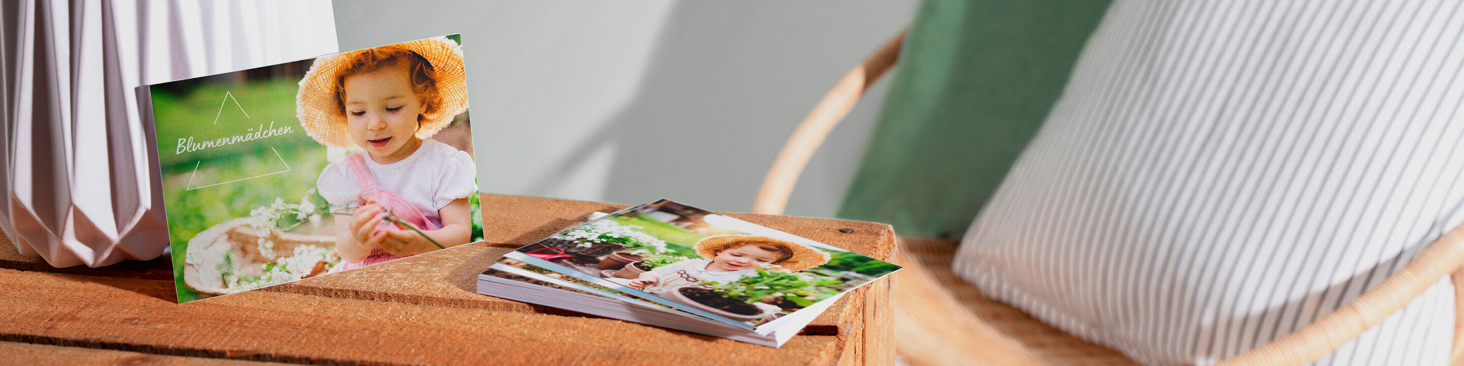 Zwei CEWE Fotobücher auf einem Tisch, das eine zeigt eine Frau mit Blumen, das andere ein Gartenmotiv
