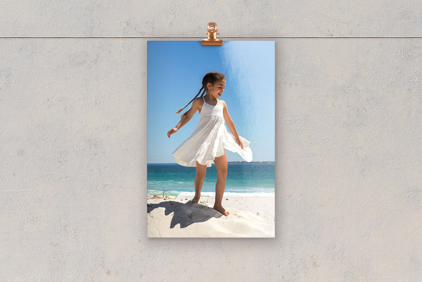 Spielende Mädchen im weißen Kleid auf einem Sandstrand.
