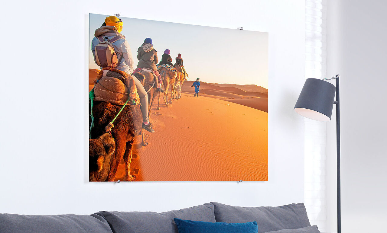 Menschen reiten auf Kamelen durch die Wüste bei Sonnenuntergang, die sandige Landschaft strahlt Wärme aus.
