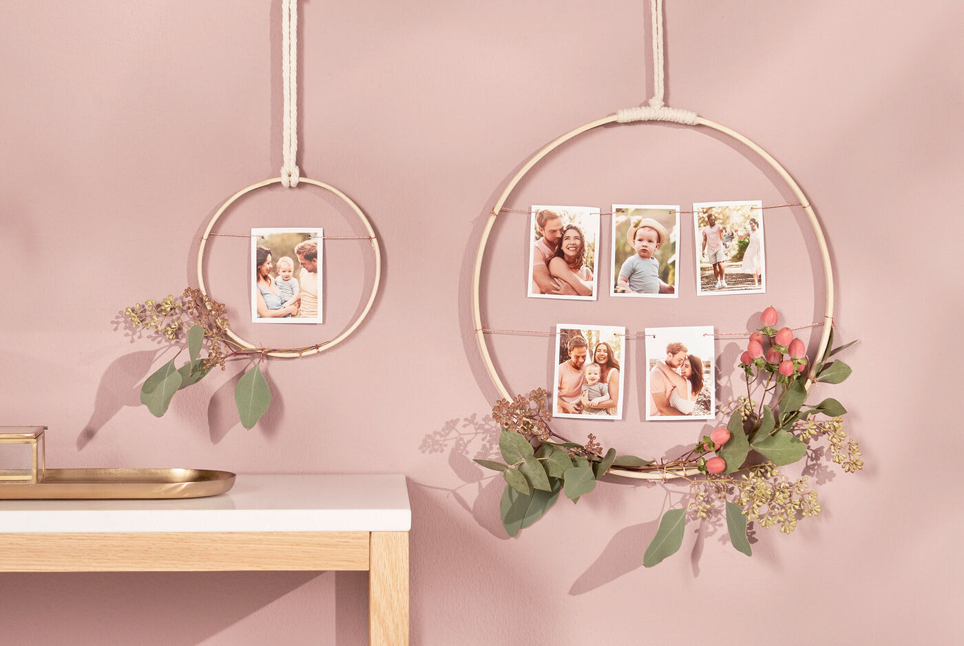 Zwei runde Bilderrahmen mit Fotos von glücklichen Familienmomenten und frischen Blumen an einer rosa Wand