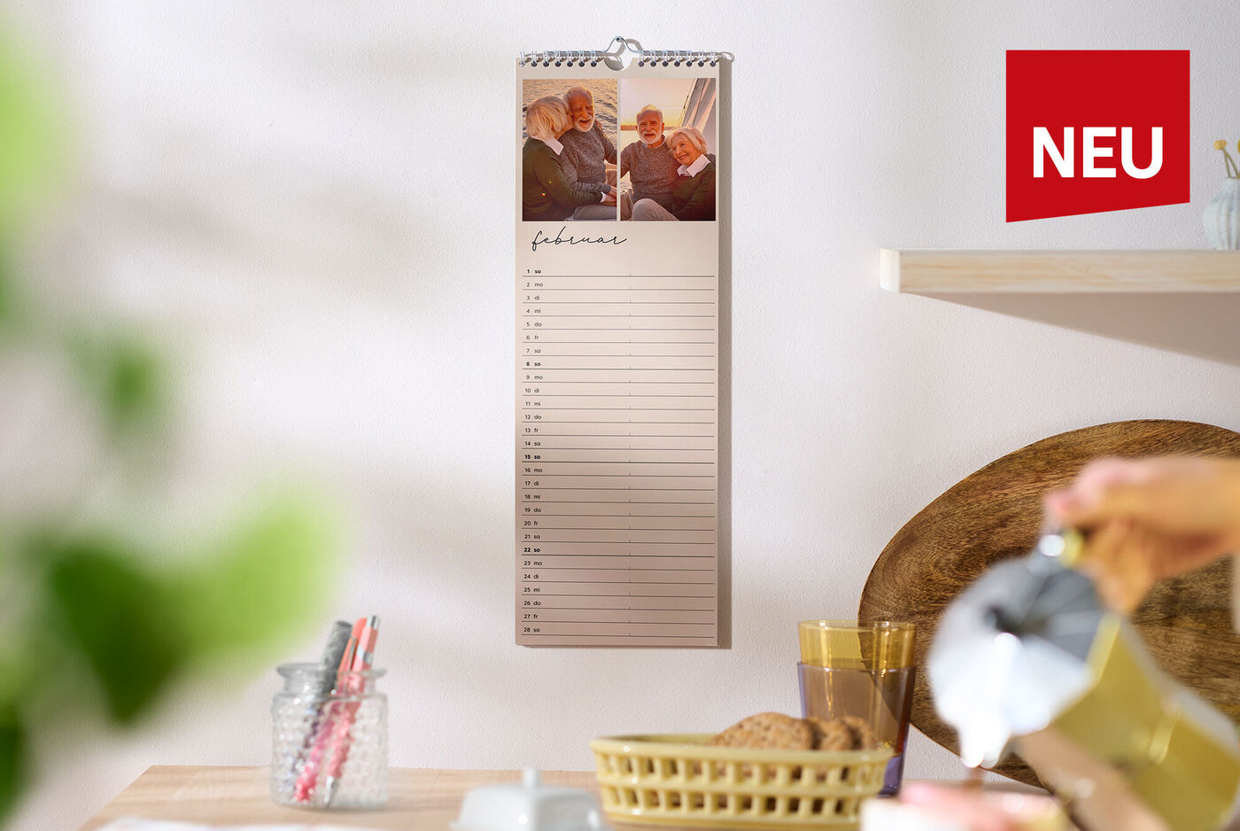 CEWE Fotokalender mit zwei Familienbildern hängt in heller Küche