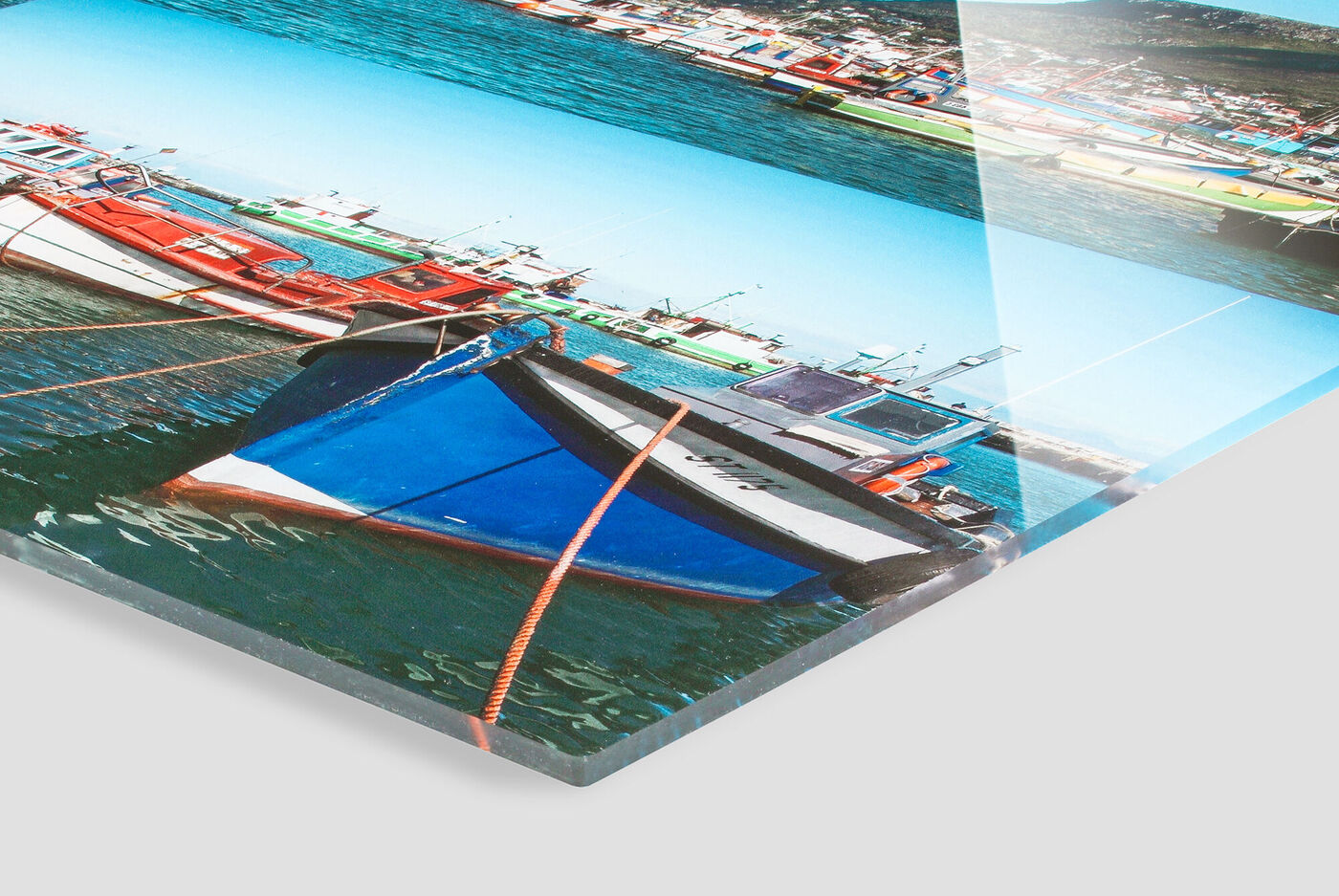 Bunte Boote, die in einem klaren Wasser liegen, mit Sonnenschein und blauen Himmel im Hintergrund