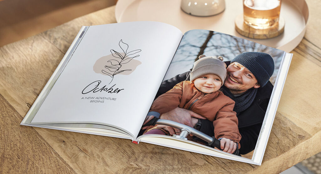 Offenes Fotobuch mit einer persönlichen Botschaft und einer warmen Familienaufnahme auf der Seite. Die Seite zeigt einen liebevollen Moment zwischen einem Elternteil und einem Kleinkind.