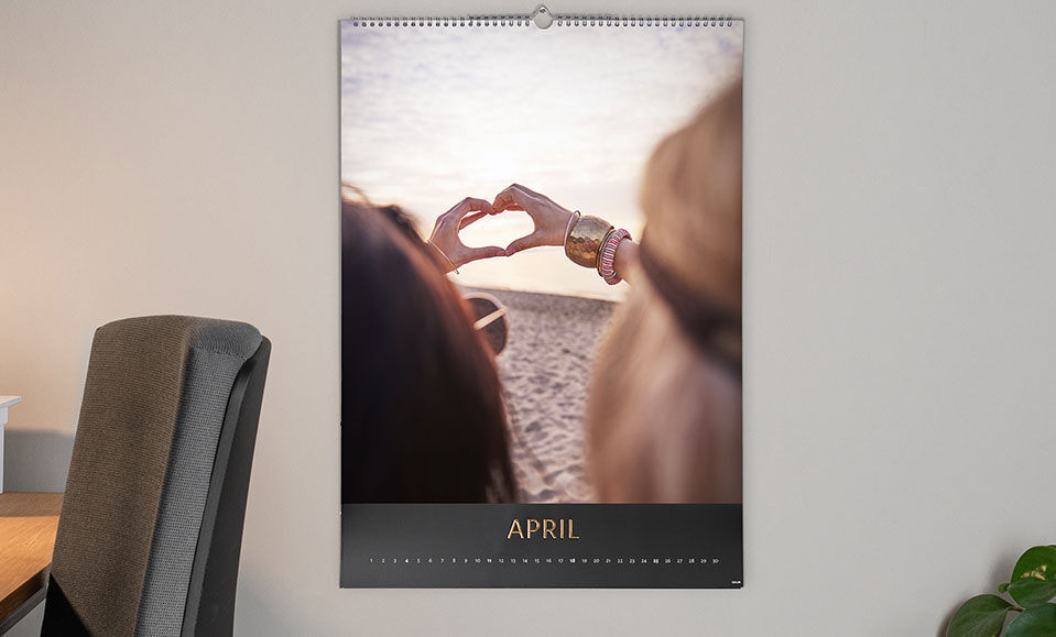 Zwei Hände bilden ein Herz vor einem Sonnenuntergang am Strand in einem Fotokalender für April.