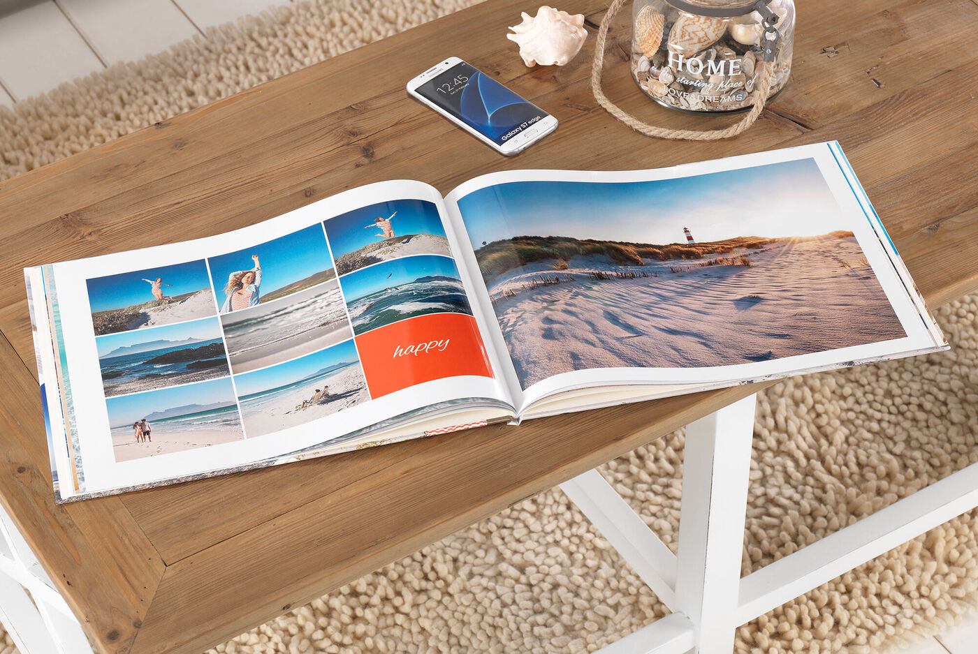 Offenes CEWE FOTOBUCH auf einem Holztisch mit Strandbildern.