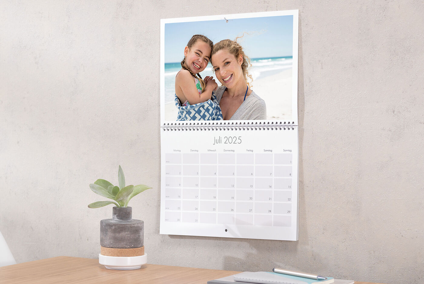 Ein individuelles CEWE Fotokalenderblatt zeigt eine Fröhlichkeit am Strand. Es ist Juli 2025.
