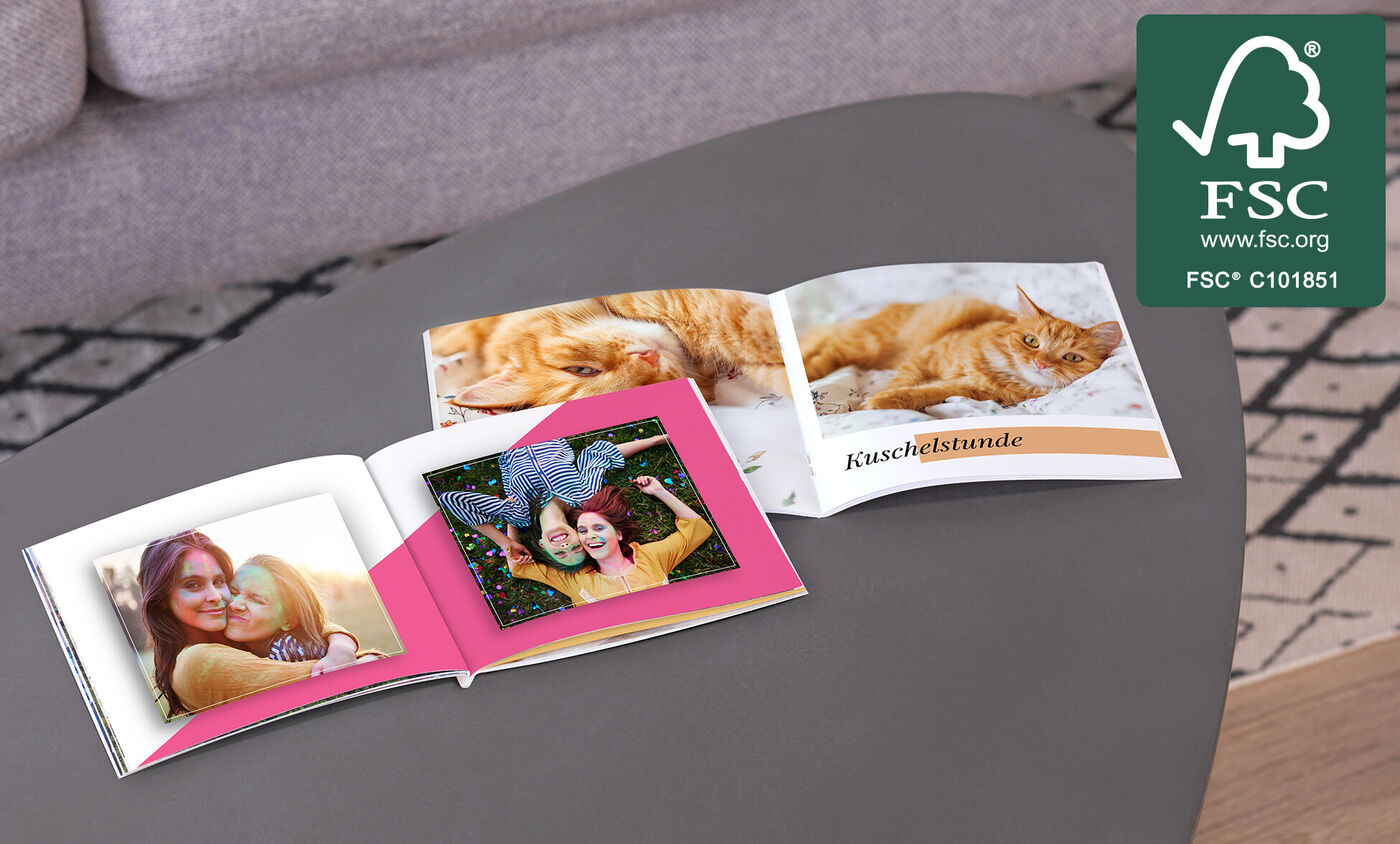 Ein offenes Fotobuch mit bunten Seiten und Fotos von glücklichen Momenten.