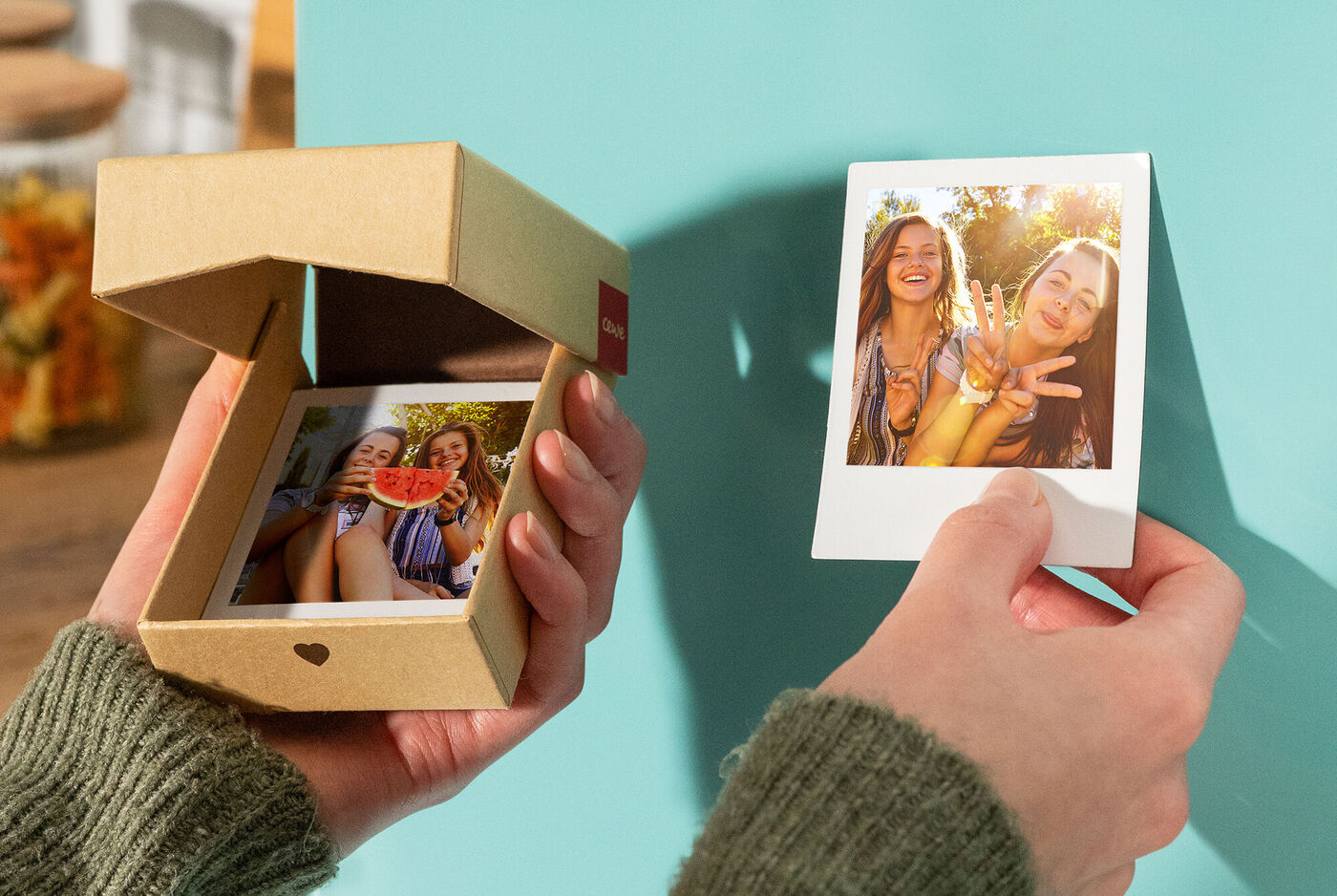 Zwei Freundinnen halten ein Foto und eine Box mit weiteren Fotos aus. Die Atmosphäre ist fröhlich und einladend.