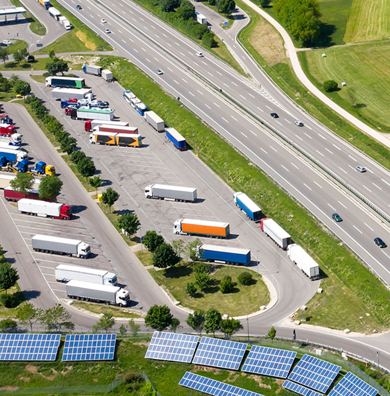 Luftaufnahme eines Parkplatzes mit vielen Lkw und Solarpanels.
