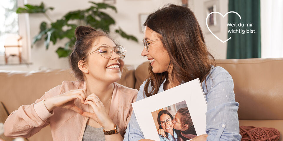 Zwei Personen sitzend auf einem Sofa, die einen Fotobuch-Schnappschuss zeigen.